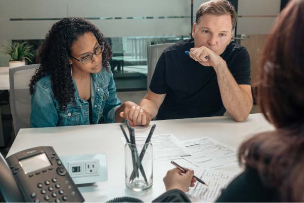 Middle-aged couple sitting with a financial advisor discussing their land investment options.