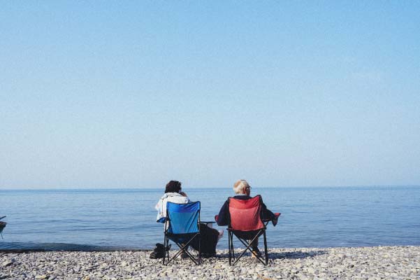 Couple sitting in fold out chairs enjoying a beautiful day on the shores of Lake Michigan.