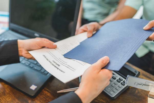 Two people discussing land financing options and handling a residential loan contract document over a desk.