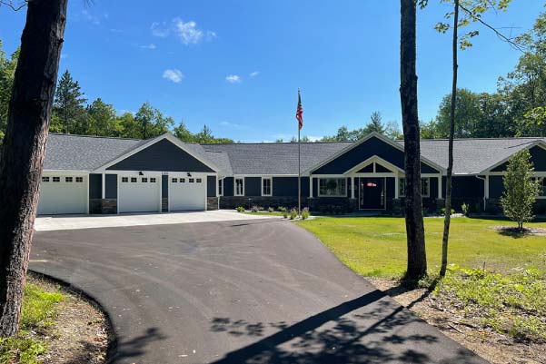 This sprawling dark blue ranch home with 4-car garage and covered porch is a perfect example of what's possible on the estate-sized parcels of property for sale in Grand Traverse County, Michigan.