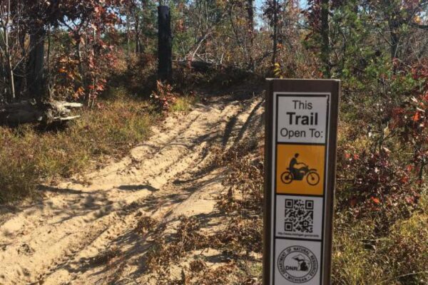 Dirt bike trail through the woods near Carpenter Creek marked by a DNR sign.