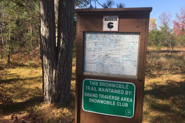 Large brown Marker 6 sign stating that the local snowmobile trail is maintained by the Grand Traverse Area Snowmobile Club.