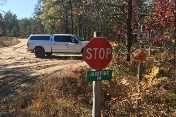 Stop sign at Jackpine road intersection with a Great Lakes Land Co. truck parked in the road.