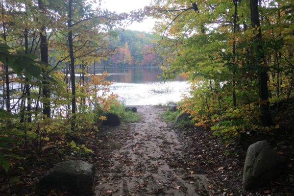 Two large rocks mark a small dirt path leading to the banks of Cook Lake.