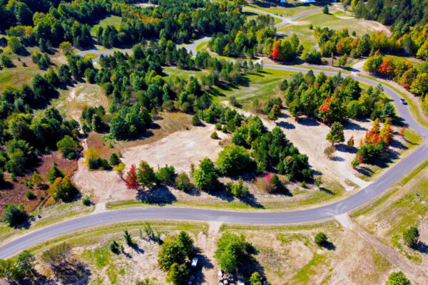 Aerial photo of a long gentle curved blacktop road and vibrant mature trees in the Paradise Ranch development near Kingsley, Michigan.