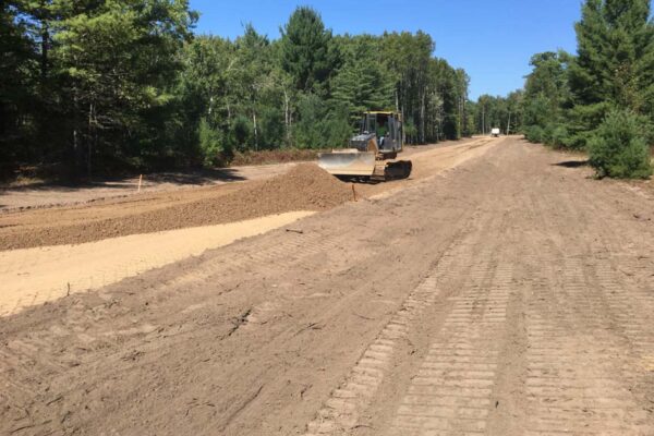 Man on a bulldozer grading a dirt road.