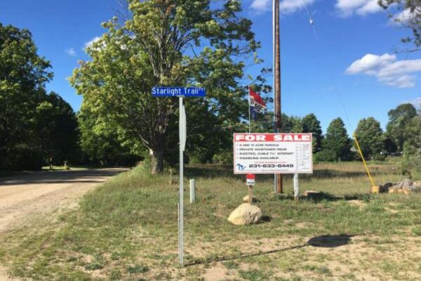 Stop sign at the end of Starlight Trail with a large For Sale sign for all remaining lots at the property development.