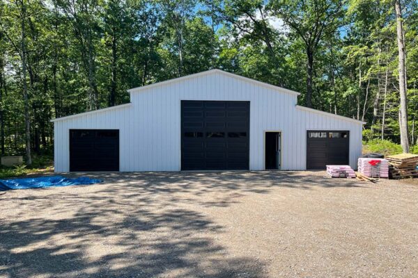 White polebarn structure with mature hardwood trees in the background at the Woodland Trails property development.
